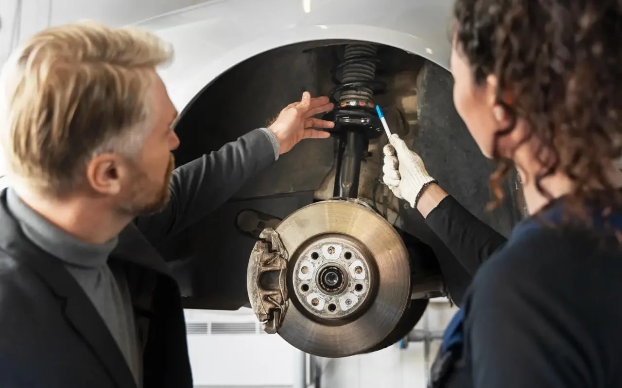 Homem e mulher na oficina a ver os amortecedores de um carro