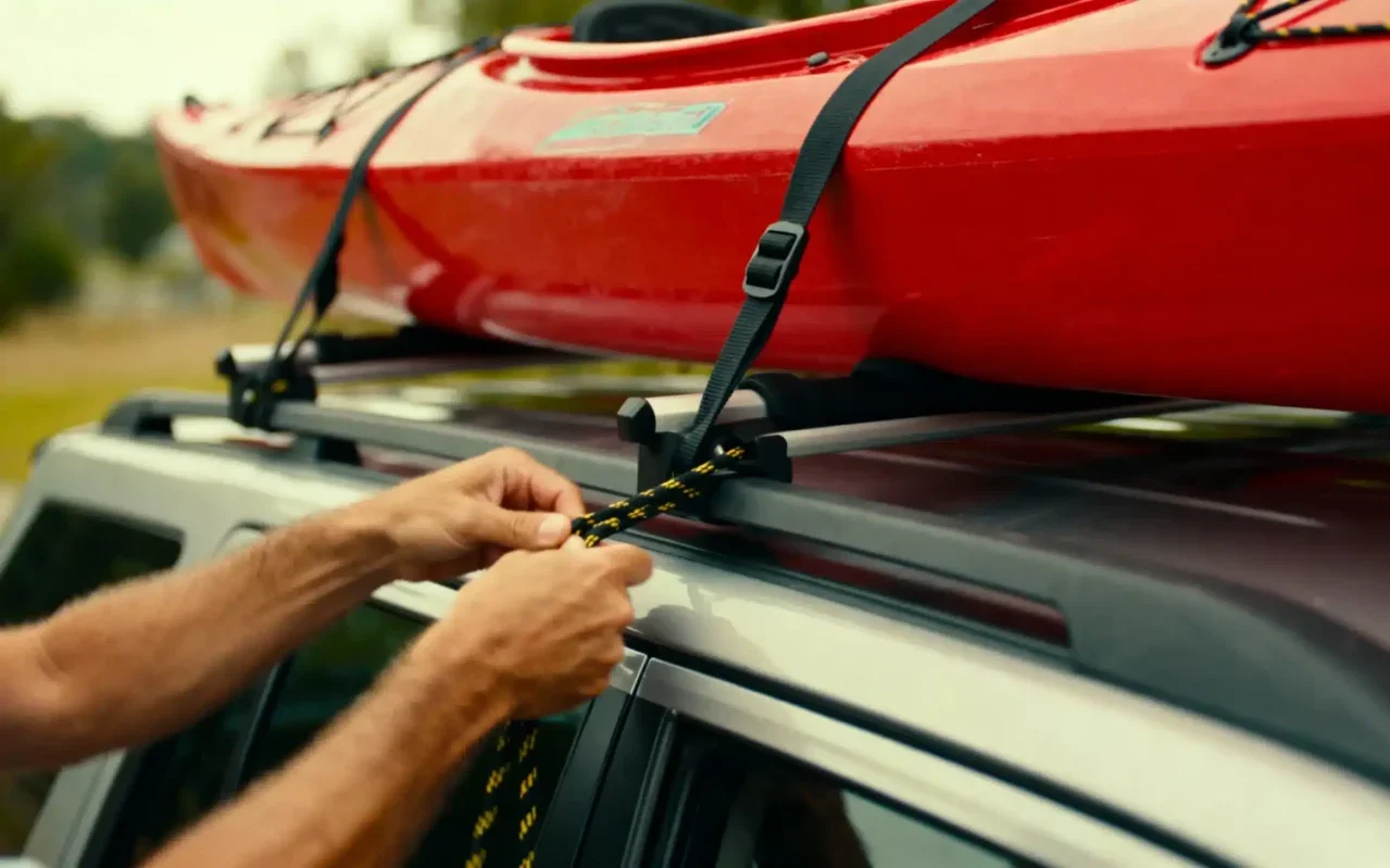 homem a prender kayak no tejadilho do carro