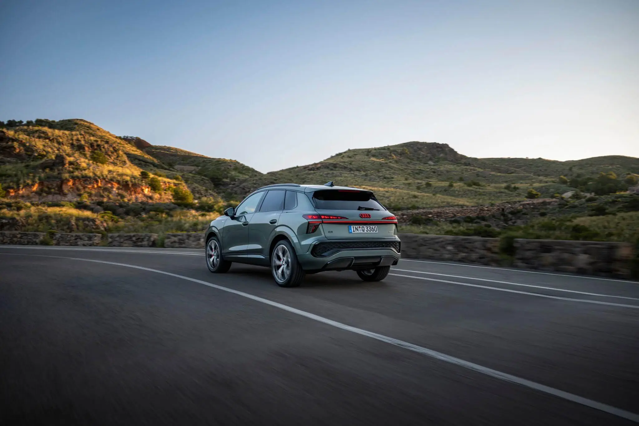 Vista traseira de um Audi Q3 e-hybrid na estrada com uma vista montanhosa