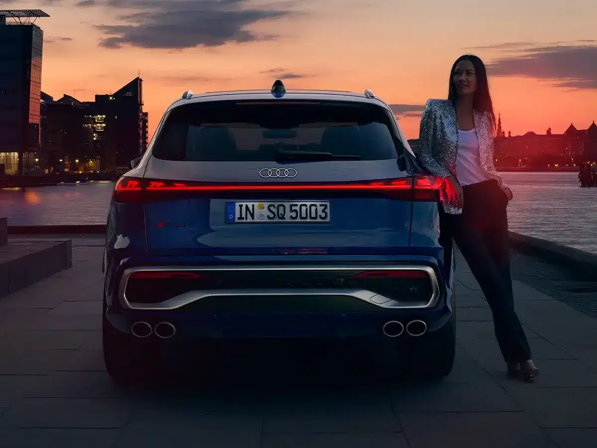 Audi SQ5 visto de traseira com mulher encostada ao carro