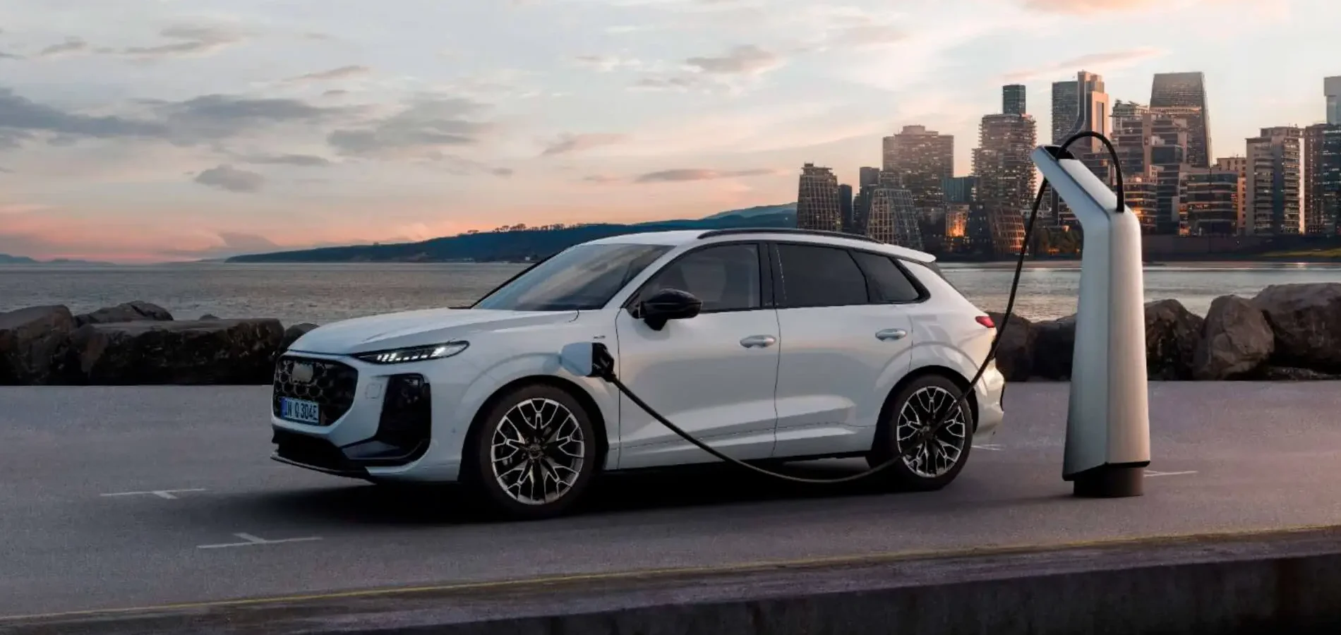 Audi Q3 e-Hybrid branco a carregar a bateria elétrica com uma paisagem citadina por trás