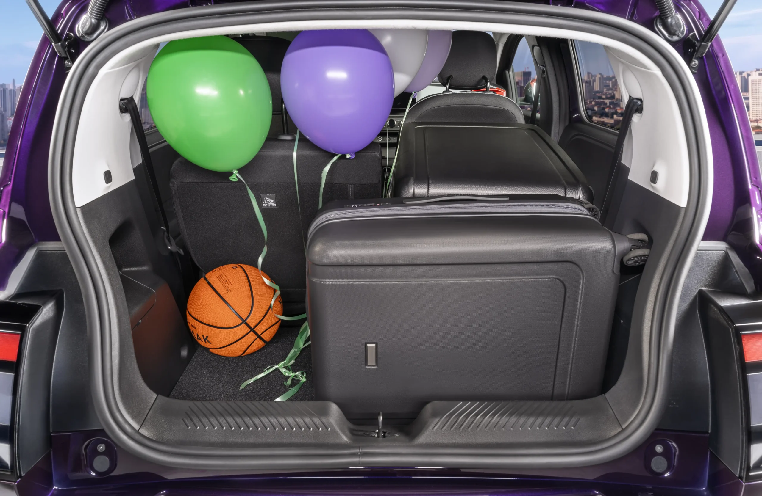 Vista da bagageira aberta do Nissan PIXO com malas, balões e uma bola de basquetebol dentro