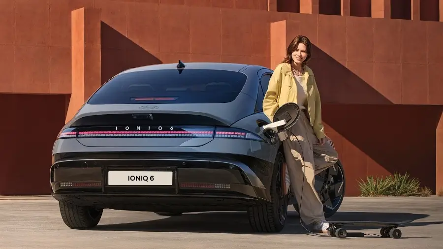 Mulher encostada ao Hyundai Ioniq 6 visto de traseira