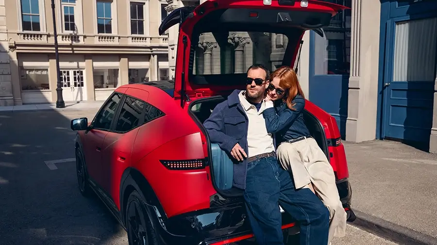 Casal sentado na bagageira aberta do Hyundai IONIQ 3 vermelho