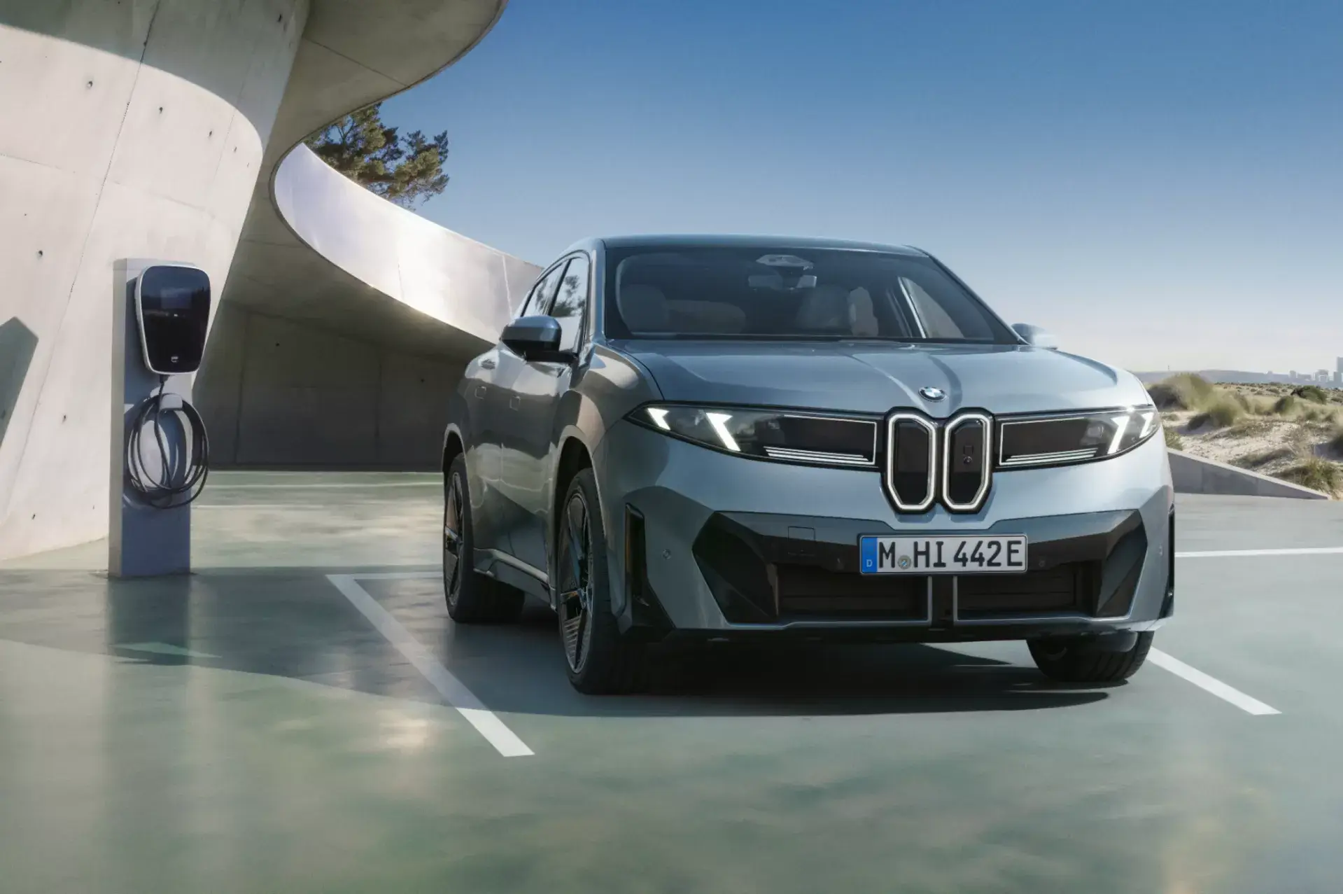 BMW iX4 ao lado de carregador elétrico