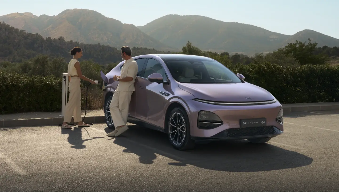 XPENG G6 a carregar com homem e mulher a falar ao lado dele