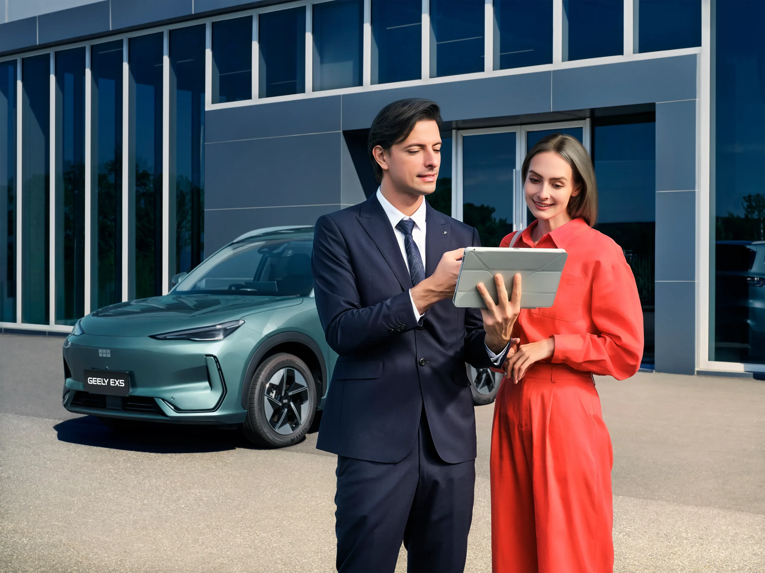 Vendedor a falar com cliente num concessionário Geely a mostrar lhe informação num tablet com carro atrás